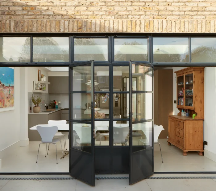 Charming open-plan dining area with black-framed glass doors and a cozy mix of rustic and modern elements.