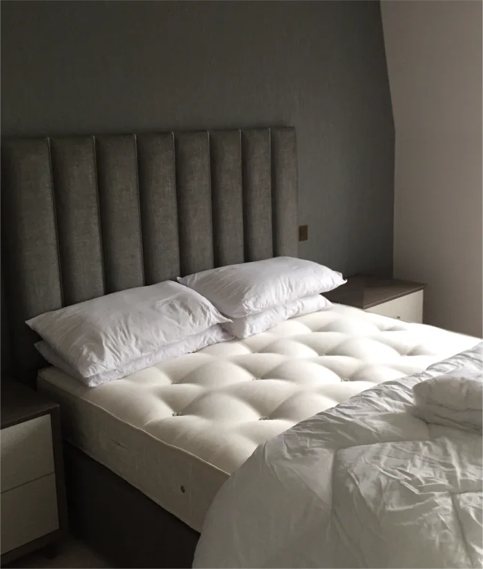 Modern bedroom with a tufted mattress, padded headboard, and cozy bedside tables for ultimate comfort.