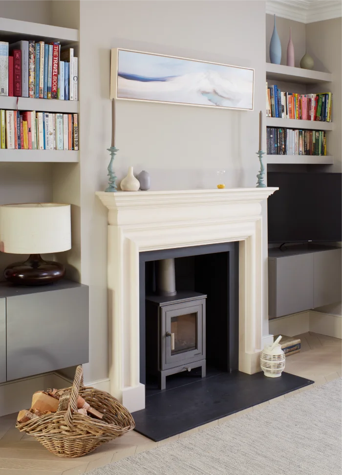 Elegant fireplace with a modern wood burner, built-in shelves, and a wicker basket