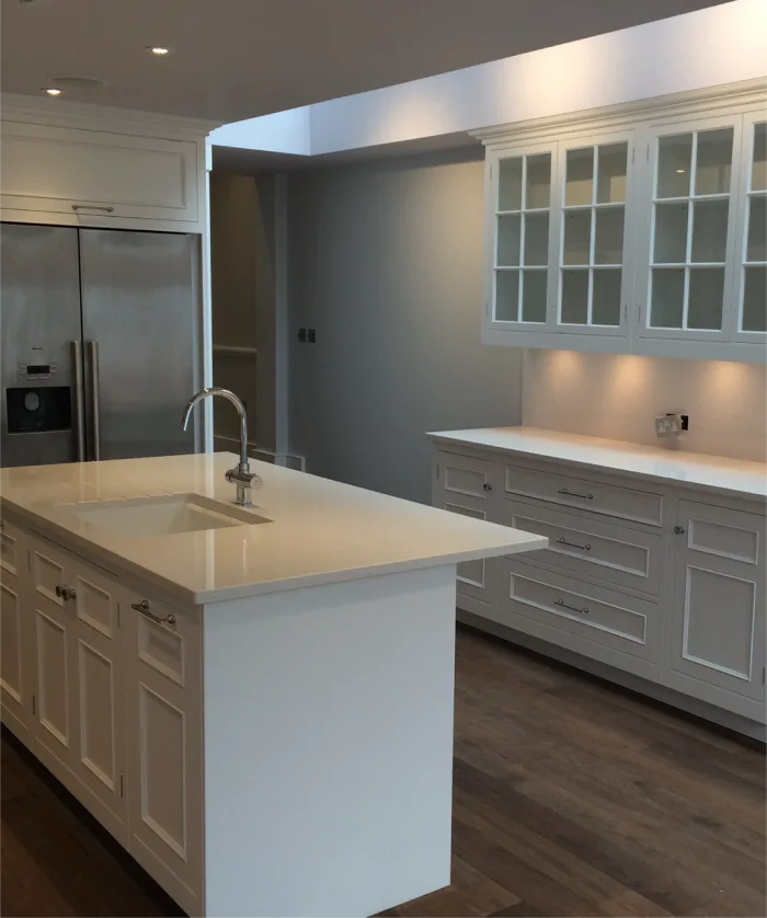 Spacious kitchen design featuring a central island with a sink, glass-front cabinets, and modern lighting accents.