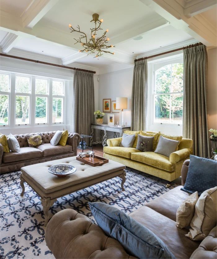 Elegant living room with large windows, cozy sofas, patterned rug, and a decorative chandelier