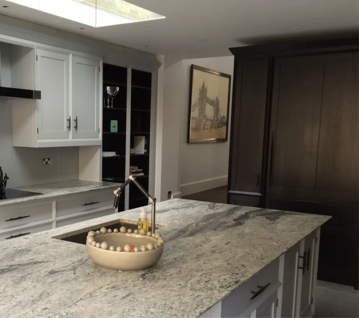 Modern kitchen with marble countertops, sleek cabinetry, and a stylish bowl centerpiece under natural light.