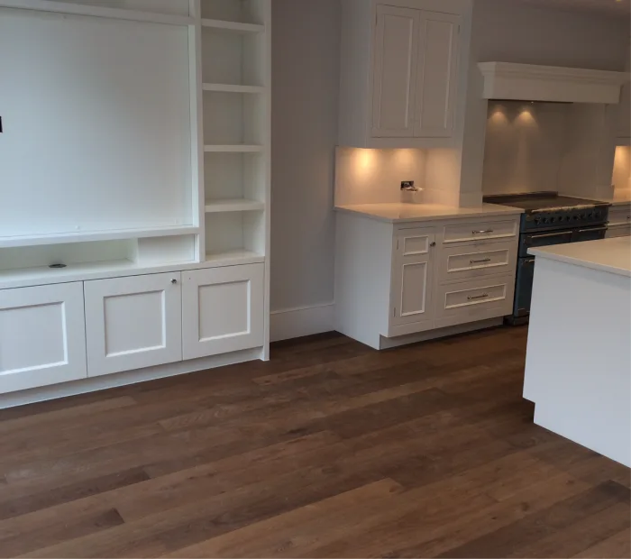 Modern kitchen with white cabinetry, built-in shelves, and warm wooden flooring for a cozy ambiance.