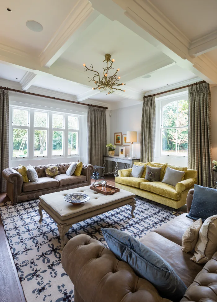 Bright and elegant living room featuring large windows, stylish furniture, and a modern chandelier for cozy ambiance.