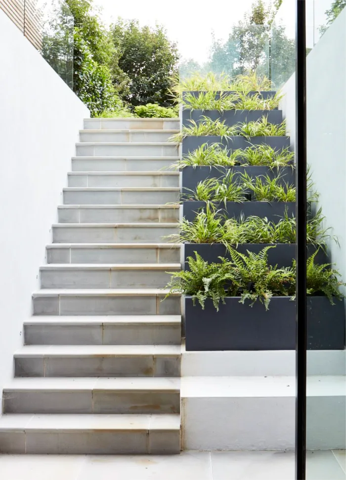 Elegant outdoor stairs with vertical planters filled with lush greenery, leading to a serene garden area.