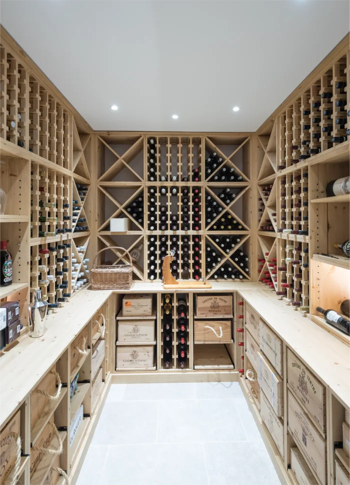 Custom-designed wine cellar with wooden racks, storage boxes, and spotlights creating a sophisticated ambiance.