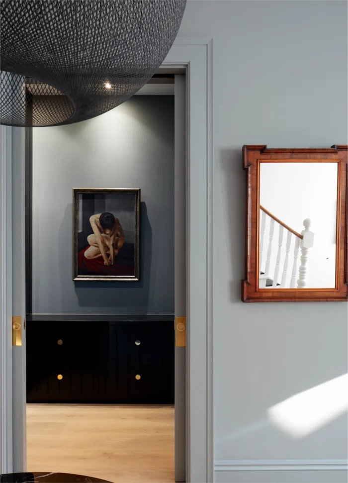 Interior hallway featuring a modern black pendant light, framed art, and wooden accents with a minimalist design.