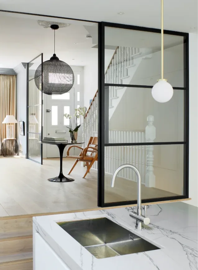 Modern kitchen sink with marble countertop and a view of a stylish hallway with glass partitions.