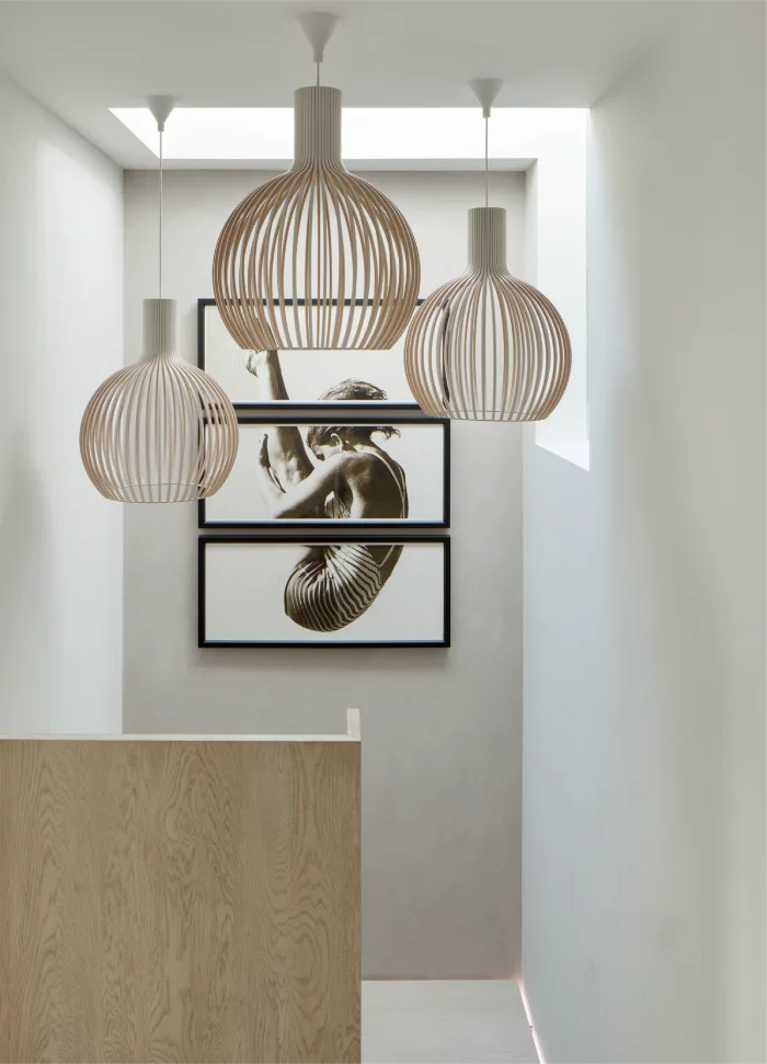 Elegant hallway with artistic pendant lights and framed modern art featuring minimalist wooden accents and design.