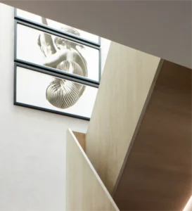 Modern loft conversion with elegant wooden staircase and artistic framed wall art for a stylish interior design.