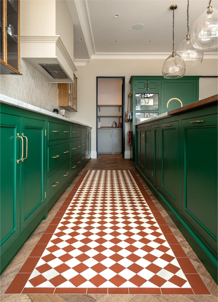 Elegant kitchen with vibrant green cabinets, a patterned tiled floor, and glass pendant lights for a modern touch.