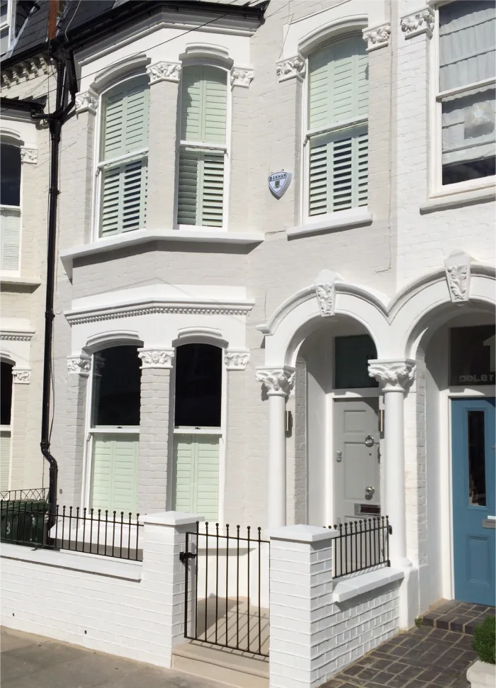 Elegant Victorian townhouse with crisp white facade, arched windows, and decorative details for timeless charm.