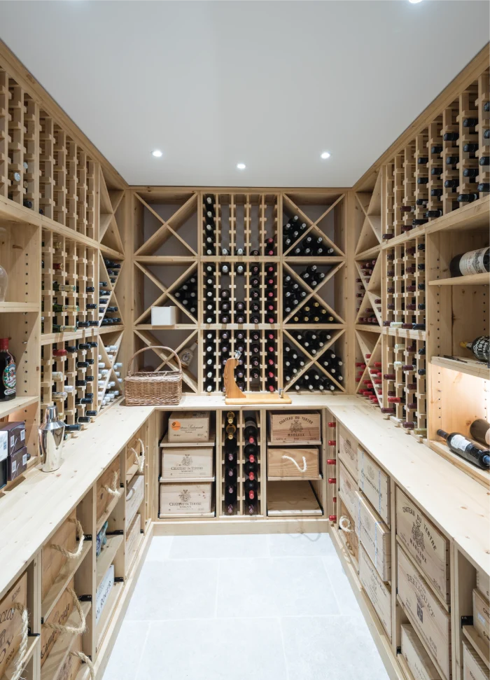 Spacious wine cellar with wooden racks, shelves, and crates, showcasing an extensive wine collection.